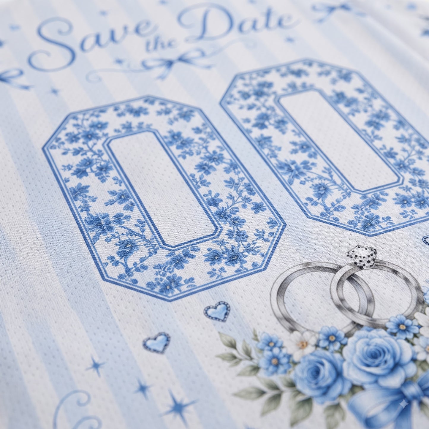 A close-up of a blue and white floral 'Save the Date' wedding invitation card design, featuring large decorative number placeholders, silver wedding rings, and blue roses.
