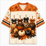 A short-sleeve V-neck t-shirt with a detailed autumn harvest graphic. The design features orange and cream sections with illustrations of pumpkins, acorns, maple leaves, and decorative bows on the front and sleeves.