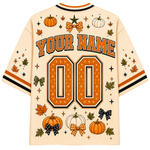 A cream-colored mesh baseball-style jersey shown from the back, featuring customizable orange and black text reading 'YOUR NAME' and '00', surrounded by autumn-themed graphics including pumpkins, stars, leaves, and bows.