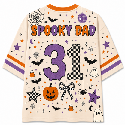 A cream-colored short-sleeve t-shirt with a colorful 'Spooky Dad 31' Halloween graphic print on the back, featuring pumpkins, ghosts, bats, stars, and stripes.