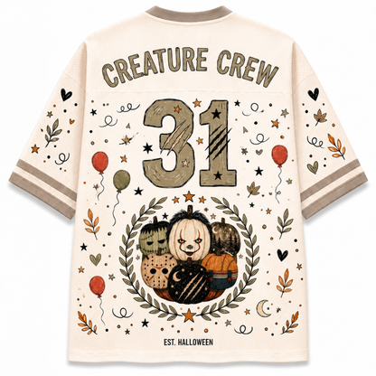 A cream-colored short-sleeve t-shirt with a Halloween-themed graphic print on the back. The design features the text 'CREATURE CREW' and 'EST.
