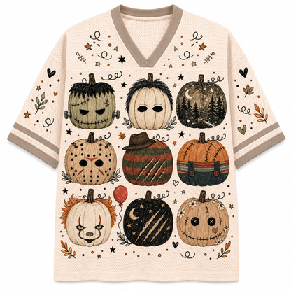 A short-sleeve V-neck knit top with a cream base and a detailed graphic print of nine whimsical, stitched Halloween pumpkins in various colors and expressions, accented with small autumn leaves, stars, and hearts.