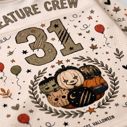 Close-up of a white Halloween-themed printed garment or fabric featuring the number 31, a wreath with pumpkins, stars, leaves, and partial text reading 'Creature Crew' and 'Halloween'.