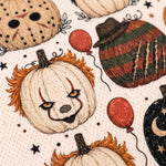 Close-up of a Halloween-themed fabric print featuring clown pumpkins, striped pumpkins, red balloons, stars, and dots on a light beige background.