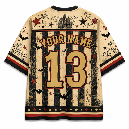 Back view of a distressed Halloween-themed short-sleeve t-shirt. The cream-colored shirt features black vertical stripes, red and black stars, bat silhouettes, a haunted house graphic, and customizable text 'YOUR NAME' and number '13' in a gold and red font.