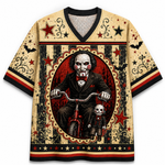 A short-sleeve V-neck t-shirt featuring a detailed graphic print of Leatherface on a red tricycle with Billy the Puppet in front, set against a distressed beige, black, and red circus-style background.
