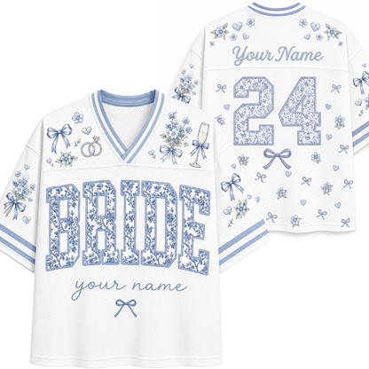White and light blue custom football-style jersey shown from the front and back, with floral-patterned 'BRIDE' lettering, the number 24, script 'Your Name', and small bow and floral motifs.