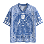 A blue and white short-sleeve V-neck t-shirt featuring a 'The Coven' tarot card design with a full moon, coven figures, and ornate celestial patterns.