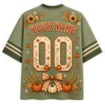 The back of an olive green short-sleeve athletic-style shirt with a personalized fall theme. The design features 'YOUR NAME' and '00' in orange varsity lettering, decorated with pumpkins, autumn leaves, sunflowers, and a gingham bow on a solid green mesh fabric.