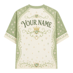 A short-sleeve t-shirt with a custom print area on the back, featuring a sage green and cream color scheme with a crown, ring, and floral scroll designs, and the text 'YOUR NAME'.