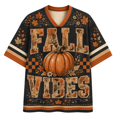 A short-sleeve V-neck t-shirt with a fall-themed graphic print. The shirt features a large orange pumpkin in the center, surrounded by the words 'FALL VIBES' in a distressed, rustic orange and beige font.