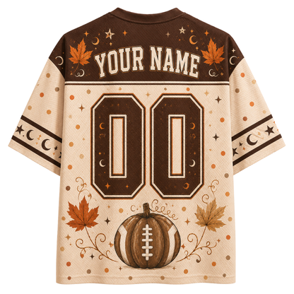 A custom athletic-style jersey shirt shown from the back, featuring a cream and brown color scheme with autumn-themed graphics including a pumpkin, maple leaves, stars, moons, and the text 'YOUR NAME' and '00'.