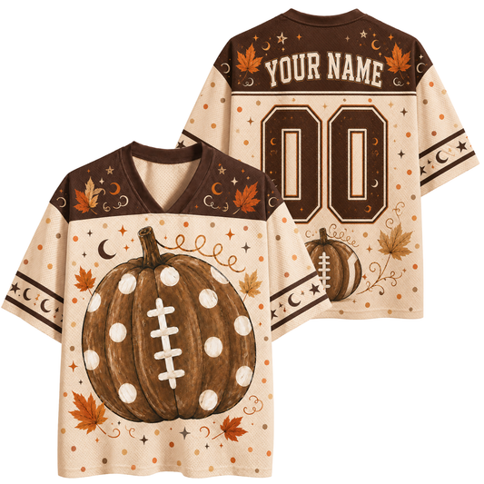 A custom football-style jersey shown from both front and back on a plain white background. The shirt has a cream base with brown shoulder panels, a large brown polka-dotted pumpkin with white laces on the front, autumn leaves, stars, moons, and decorative dots.