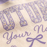 Close-up of a cream-colored knit fabric with purple text reading 'FUTURE Your Na.