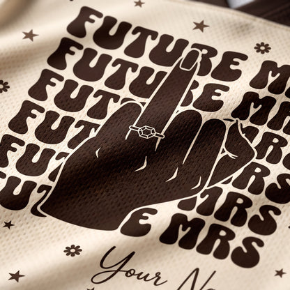Close-up of a cream-colored mesh fabric with a dark brown graphic print featuring the word 'FUTURE MRS' repeated, a hand silhouette, stars, and partial script text reading 'Your N.