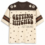 A retro-style short-sleeve t-shirt with a cream and dark brown color-blocked design. The back features the text 'GETTING HITCHED EST.