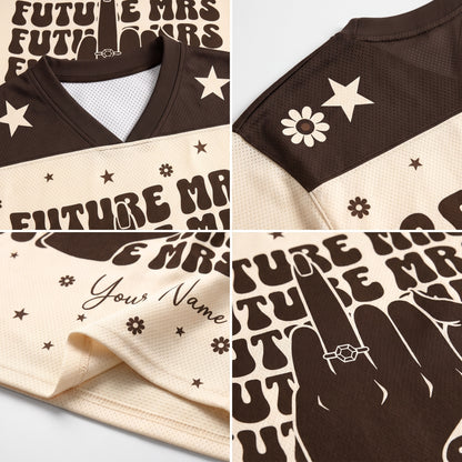 A close-up collage of a brown and cream mesh sports jersey showing printed graphics, including 'FUTURE MRS.', stars, flowers, script text, and a ring graphic.