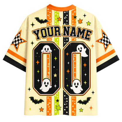 A Halloween-themed short-sleeve jersey-style shirt shown flat against a white background. The shirt has a cream base with orange, black, green, and yellow graphic accents, including stars, stripes, bats, ghosts, checkered stars, and large customizable text reading 'YOUR NAME' above two large '00' blocks.