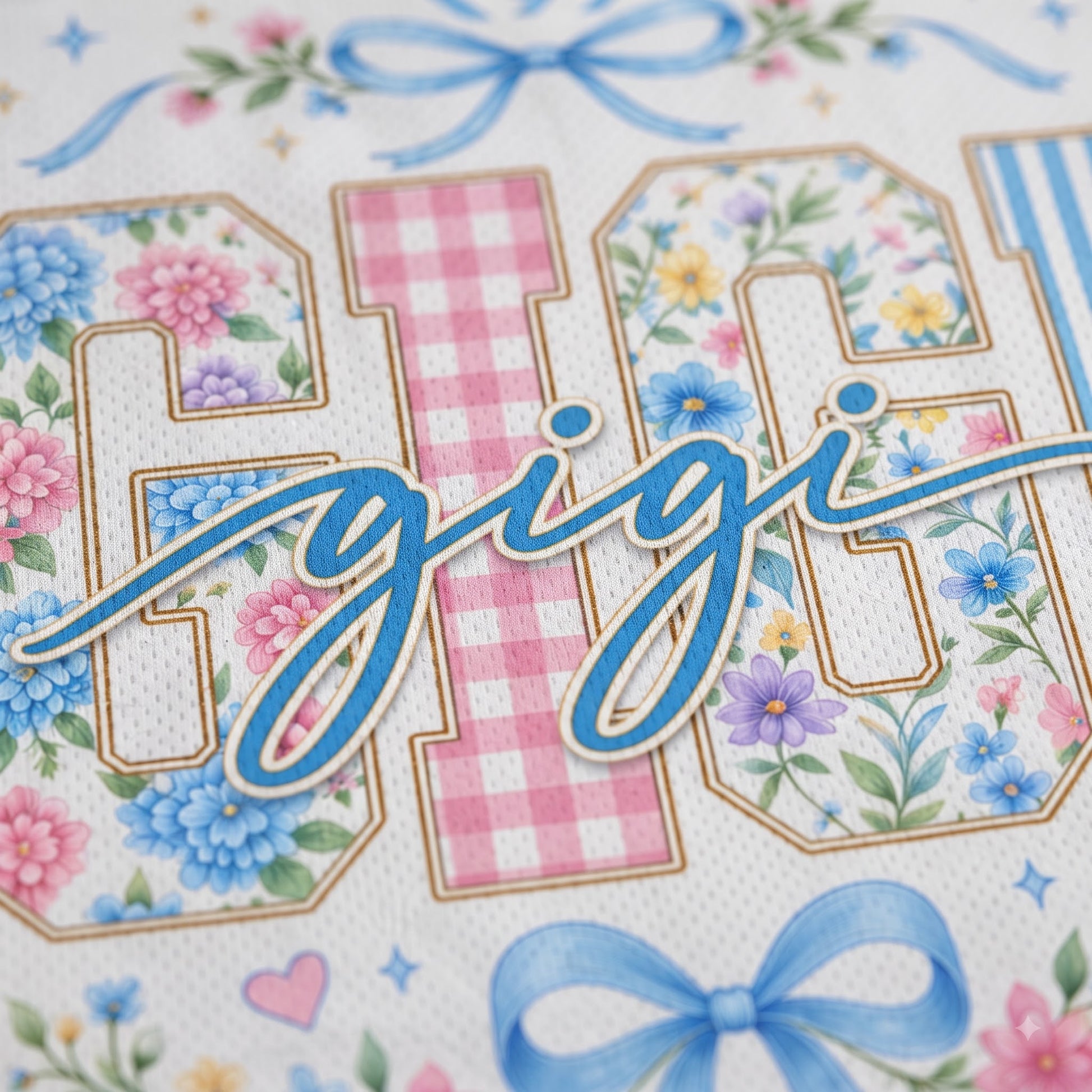 A close-up of a decorative printed surface featuring large floral and gingham-style letters with blue script text across the center, plus blue bows and small floral accents on a white background.