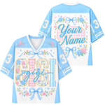 A short-sleeve t-shirt with a Halloween-themed graphic print on the back. The design features a cream-colored top panel with butterflies and floral borders, a dark brown lower body, and a central graphic of a cute ghost wearing an orange bow and holding a jack-o'-lantern basket, surrounded by flowers and the text 'Your Name'.