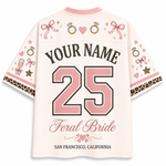 A custom short-sleeve t-shirt shown from the back, featuring a light pink base with a variety of bridal-themed graphics including pink bows, engagement rings, hearts, champagne glasses, and leopard print cuffs. The shirt is personalized with the text 'YOUR NAME', the number '25' in pink, 'Feral Bride', and 'SAN FRANCISCO, CALIFORNIA'.