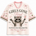 A women's short-sleeve V-neck t-shirt in a light pink mesh fabric, featuring a bachelorette-themed graphic print of a raccoon wearing heart-shaped sunglasses and holding a champagne glass. The text reads 'GIRLS GONE Feral', 'OLIVIA'S BACHELORETTED', 'San Francisco, California', and 'EST.