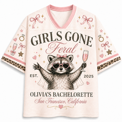 A women's short-sleeve V-neck t-shirt in a light pink mesh fabric, featuring a bachelorette-themed graphic print of a raccoon wearing heart-shaped sunglasses and holding a champagne glass. The text reads 'GIRLS GONE Feral', 'OLIVIA'S BACHELORETTED', 'San Francisco, California', and 'EST.