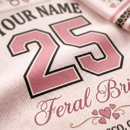 Close-up of a white mesh sports jersey with pink and black custom text, featuring the number 25 and the words 'YOUR NAME' and 'Feral Bride' with small pink hearts.