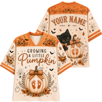 A Halloween-themed V-neck t-shirt shown from both front and back. The shirt features a cream base with orange trim, decorated with pumpkins, ghosts, bats, and the text 'GROWING A LITTLE Pumpkin' on the front, and 'YOUR NAME SINCE 2024' on the back.
