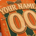 Close-up of a personalized name tape or gift wrap design with large embroidered-style numbers '00', the text 'YOUR NAME', a leopard-print bow, stars, and decorative swirls on an orange and dark green striped background.