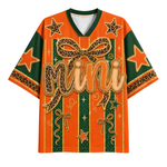 An orange and green short-sleeve V-neck t-shirt with a bold graphic design featuring leopard-print bows, stars, and the word 'Mini' in script across the front, shown on a plain white background.