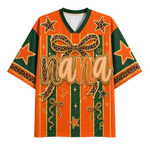 A short-sleeve V-neck graphic shirt in orange and dark green, featuring leopard-print bow and stripe details, star motifs, and the word 'Nana' across the front.