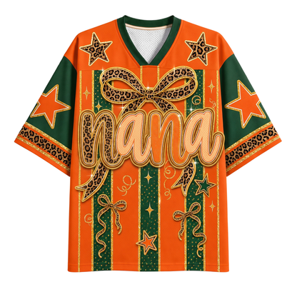 A short-sleeve V-neck graphic shirt in orange and dark green, featuring leopard-print bow and stripe details, star motifs, and the word 'Nana' across the front.