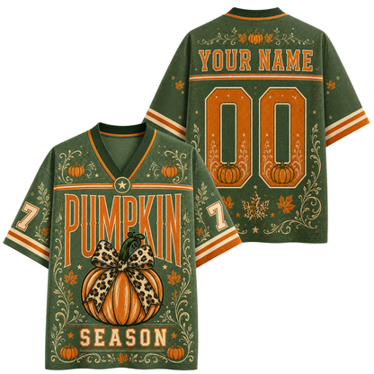 Back view of a customizable black short-sleeve jersey with orange and beige autumn-themed leaf patterns, a striped collar and cuffs, and 'YOUR NAME 10' printed in a distressed camouflage-style font.