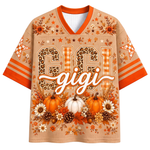 A black mesh short-sleeve jersey shown from the back, featuring customizable orange and pink text reading 'YOUR NAME' above large '00' numbers. The shirt is decorated with autumn-themed graphics including pumpkins, bows, leaves, stars, a witch hat, and a cauldron, with orange, pink, and black striped sleeve cuffs.