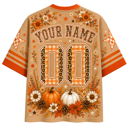 A personalized short-sleeve t-shirt with a fall theme, featuring orange and beige gingham patterns, pumpkins, autumn leaves, and customizable text 'YOUR NAME' and '00' on the back.