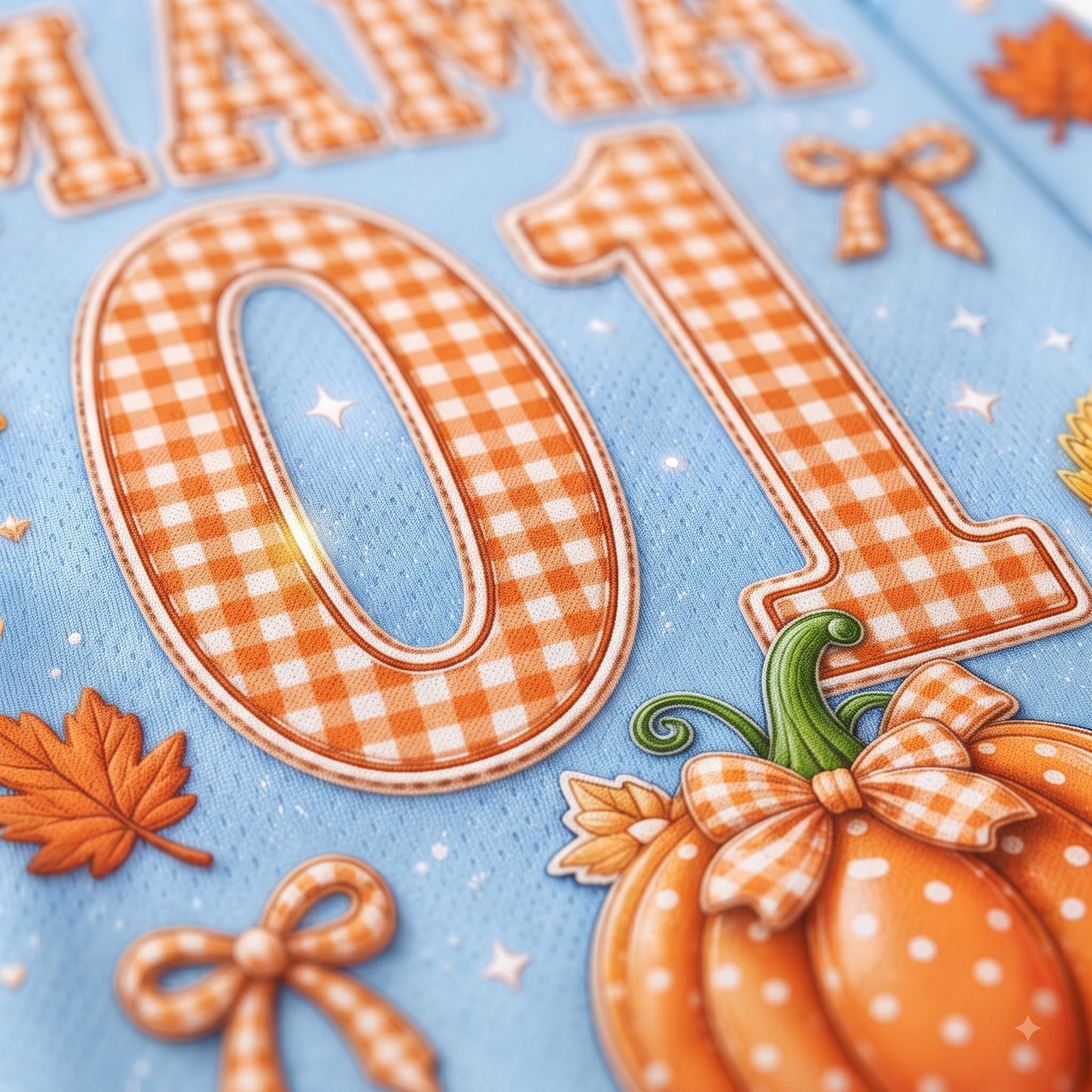 A close-up of a light blue fabric surface with large orange-and-white gingham numbers 0 and 1, autumn leaves, bows, and a pumpkin decoration.