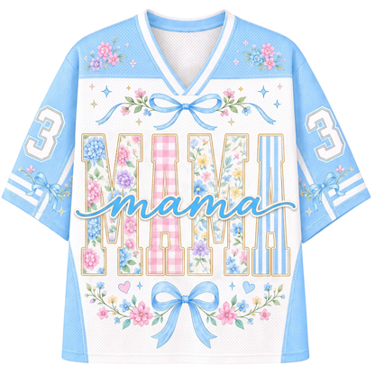 A women's short-sleeve V-neck jersey-style top in light blue and white mesh, decorated with floral patterns, bows, stars, and the word 'MAMA' across the front, with the number 3 on each sleeve.
