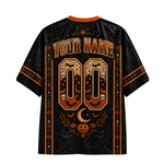Black short-sleeve t-shirt with orange and brown Halloween-themed graphic print on the back, featuring customizable text 'YOUR NAME' and number '00' with bats, skulls, pumpkins, and a crescent moon.