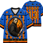 A blue and orange Halloween-themed hockey jersey shown from the front and back. The front features a graphic of a masked figure holding a bloody knife inside an oval frame, surrounded by bats, stars, and a haunted house on a striped orange and black background.