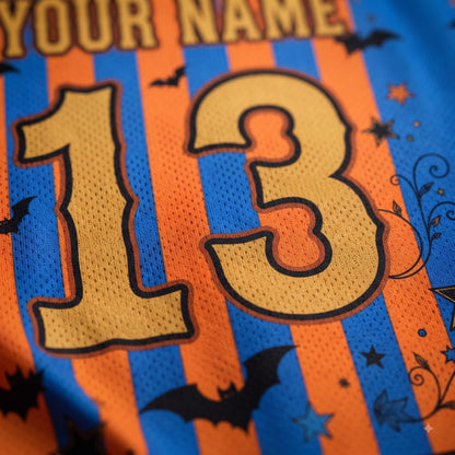 Close-up of a blue and orange striped athletic jersey with a large gold number 13, black bat silhouettes, and decorative Halloween-style graphics. Part of the text 'YOUR NAME' is visible at the top.