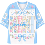 A light blue and white mesh football-style jersey with a V-neck, featuring the word 'mimi' in script across the front, large decorative block letters spelling 'MIMI' filled with floral and gingham patterns, blue bows, stars, and the number 3 on both sleeves.