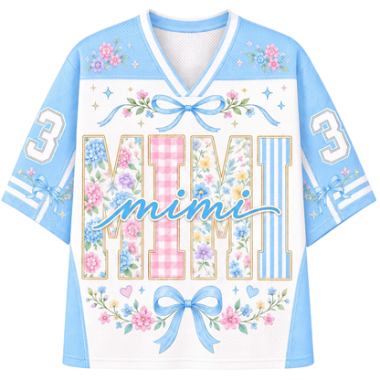 A light blue and white mesh football-style jersey with a V-neck, featuring the word 'mimi' in script across the front, large decorative block letters spelling 'MIMI' filled with floral and gingham patterns, blue bows, stars, and the number 3 on both sleeves.