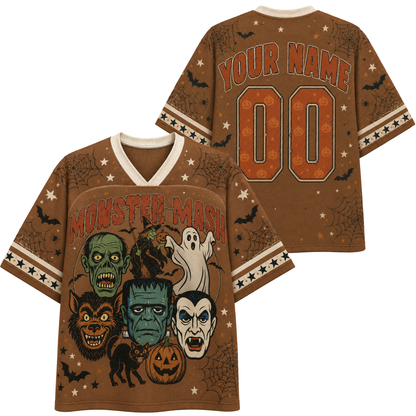 A brown short-sleeve V-neck t-shirt with a Halloween graphic print, shown in both front and back views. The front features 'MONSTER MASH' in orange text above a collage of classic horror characters including Frankenstein, Dracula, the Lurcher, a zombie, a ghost, a werewolf, and a jack-o'-lantern.