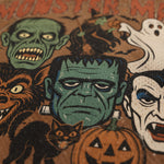 A close-up of a Halloween-themed graphic print featuring illustrated monster faces including Frankenstein's monster, a zombie, a werewolf, a ghost, and a vampire, with a jack-o'-lantern and a black cat on a brown background.
