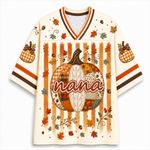 A cream-colored short-sleeve V-neck jersey-style shirt with an autumn theme, featuring a large patchwork pumpkin with the word 'nana' across the front, orange and brown vertical stripes, gingham pumpkin motifs on the sleeves, and scattered fall leaves and stars.