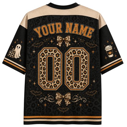 A customizable Halloween-themed short-sleeve jersey shirt shown from the back, featuring a black and beige leopard print pattern, 'YOUR NAME' and '00' placeholders, and spooky graphics like a ghost, coffee cup, and bats.
