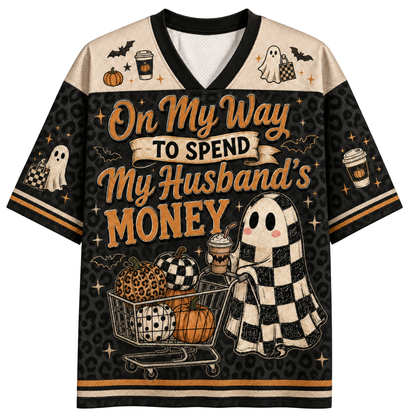 A short-sleeve V-neck t-shirt with a Halloween-themed 'MAMA' graphic. The shirt features a black body with purple and orange shoulder panels, decorated with bats, stars, and spiderwebs.