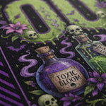 Close-up of a Halloween-themed graphic print featuring two glass potion bottles labeled 'Toxic Bloom' and 'Deadly Dose', skulls, flowers, bats, and a green dripping 'DO NOT' design on a black background.