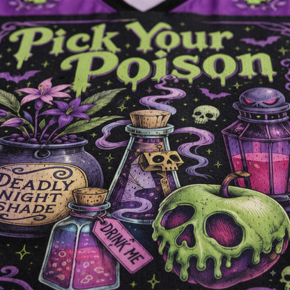 Close-up of a graphic t-shirt featuring a gothic Halloween design with the text 'Pick Your Poison' in dripping lime green font. The graphic includes a skull-faced green apple, a potion bottle labeled 'DRINK ME', a cauldron with purple flowers and the text 'DEADLY NIGHT SHADE', and other spooky elements on a black background with purple accents.